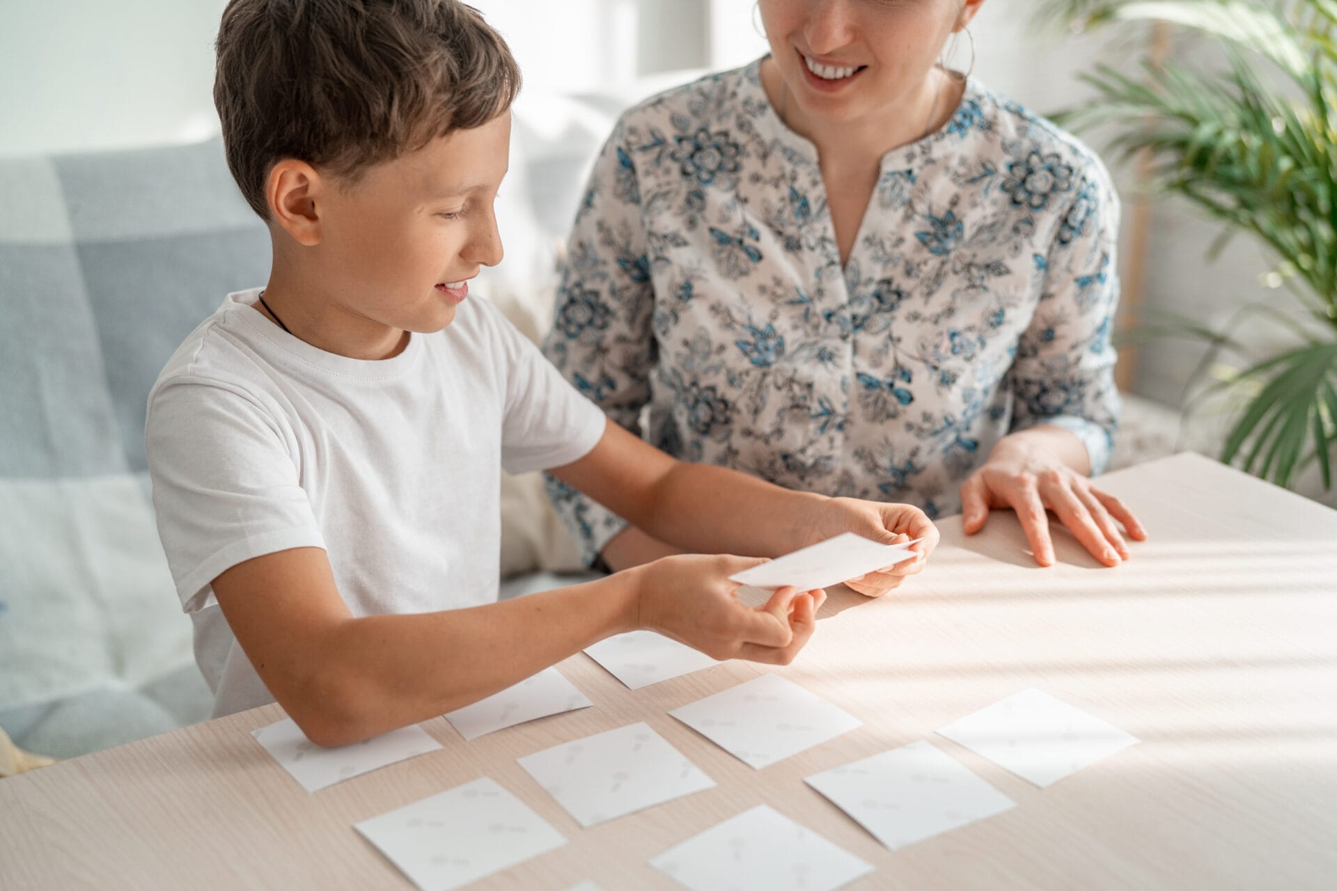 Smiling therapist and 7 year old boy playing a memory card game together. Smiling therapist and boy playing a memory card game together.