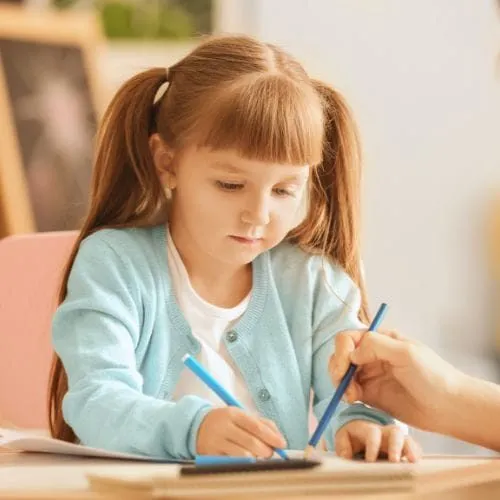 A young girl drawing with her therapist - representing the Purple House Clinic's Play & Art Therapy Services.